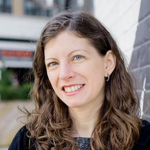 Smiling woman with long, curly brown hair.