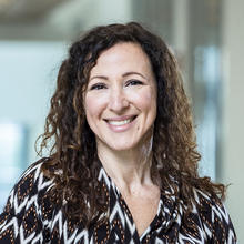 Smiling woman with long, curly brown hair.