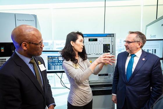 Two men and a woman in conversation in front of lab equipment